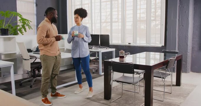 African American colleagues in office chatting and enjoying coffee break together