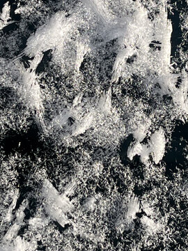 Close-up macro shot of intricate ice crystals and frost patterns on a dark surface, frozen nature, icy texture, monochrome, cold season, winter.