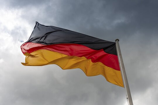 Germany flag in the wind in front of dark clouds, black-red-gold, Berlin, Germany