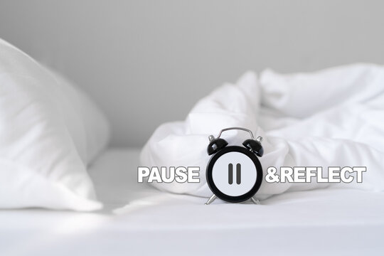 analog black clock with stop sign and pause reflect text on white messy bed with morning light