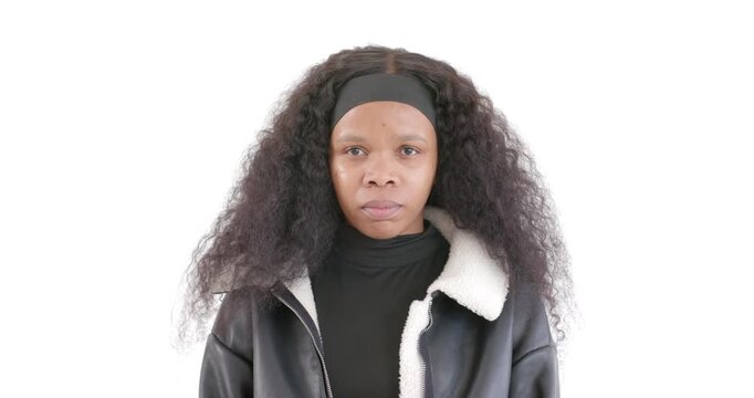 Standing against white background, confident woman in black jacket looking determined