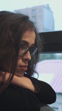 Overthinking and loneliness, sad woman in glasses resting by window. Emotional exhaustion, social isolation and stress, mental health awareness. Vertical video.