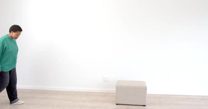 Person in green sweater standing indoors, looking forward with calm expression