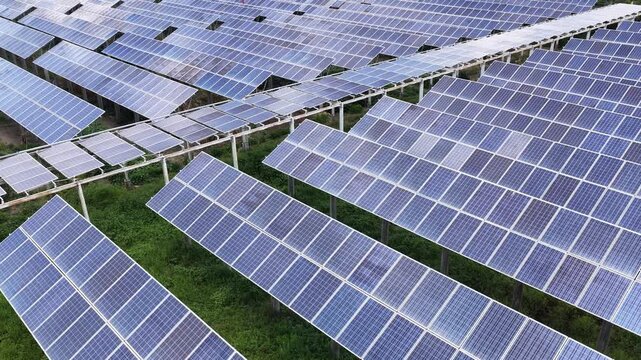 Rows of solar panels installed on green grass field for renewable energy generation