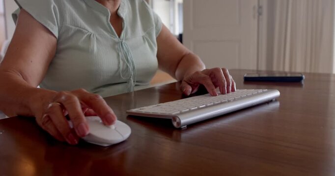 Senior woman typing on wireless keyboard at home, focusing on work