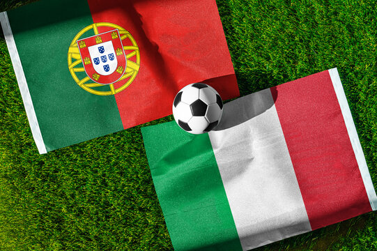 Portugal vs. Italy football match. National flags on green grass with soccer ball in the middle. Football background for international match.