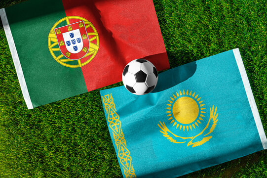 Portugal vs. Kazakhstan football match. National flags on green grass with soccer ball in the middle. Football background for international match.