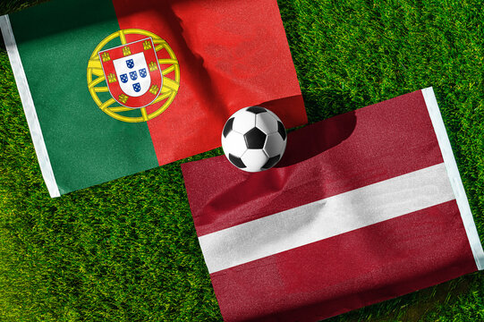 Portugal vs. Latvia football match. National flags on green grass with soccer ball in the middle. Football background for international match.