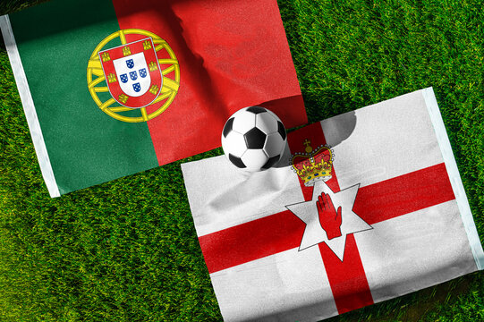 Portugal vs. Northern Ireland football match. National flags on green grass with soccer ball in the middle. Football background for international match.