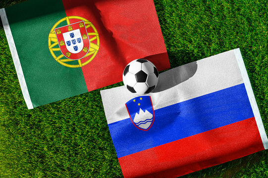 Portugal vs. Slovenia football match. National flags on green grass with soccer ball in the middle. Football background for international match.