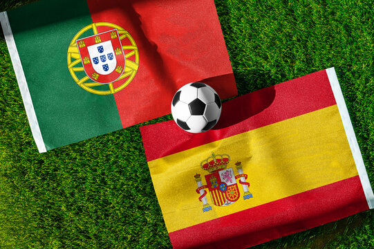 Portugal vs. Spain football match. National flags on green grass with soccer ball in the middle. Football background for international match.