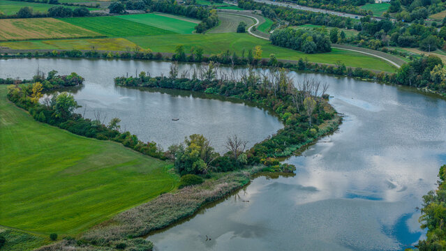 Ein Fluss verl&auml;uft durch eine gr&uuml;ne Landschaft mit B&auml;umen und Wiesen in der N&auml;he einer kleinen Stadt
