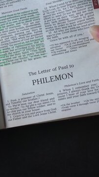 Opening to the book of Philemon of the New Testament in the Holy Bible. New Revised Standard Version. Vertical video.
