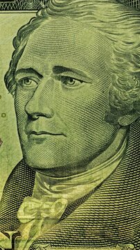 Alexander Hamilton portrait under green scan. Portrait on ten dollar bill glows as green security scan moves across banknote. 