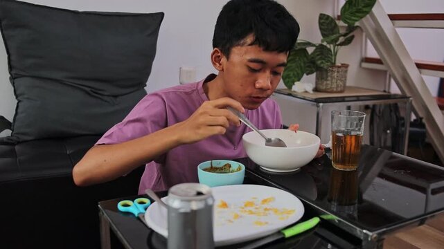 Close view of man eating batagor soup with spoon while sitting on floor