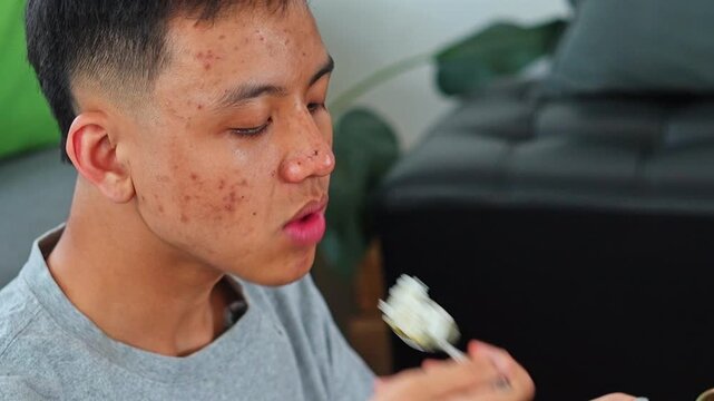 Close up of young man eating food and drinking orange juice at home