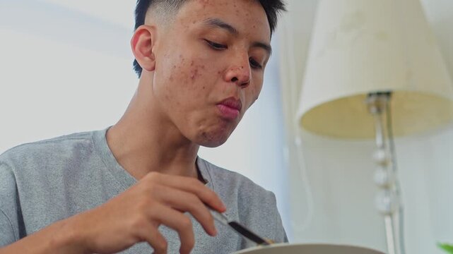 Close-up of young man eating karedok or traditional indonesian salad with spoon