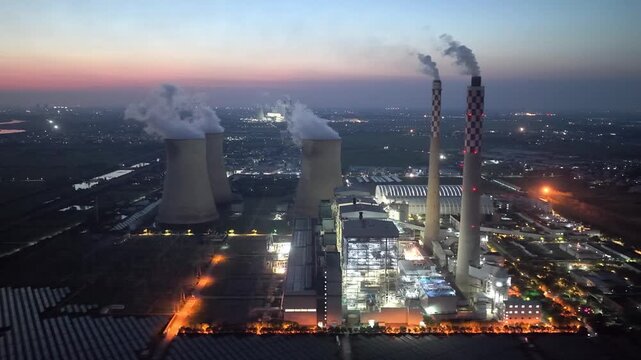 thermal power plant at dusk with cooling towers and smoke stacks