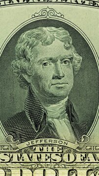 Thomas Jefferson bill under green security scan. Green scan light moves across Thomas Jefferson bill making banknote glow. This anti counterfeit effect reveals portrait layers as image shifts.