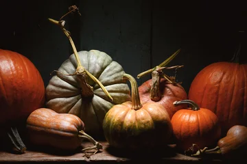 Mixed pumpkins arranged on wooden table in dark moody lighting. Autumn harvest still life with squash and seasonal vegetables © Ivan Kmit