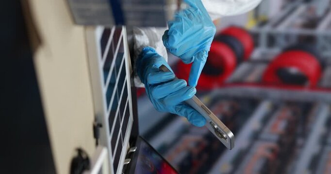Close-up of a worker in blue gloves scanning a package with a handheld barcode reader beside a delivery locker.