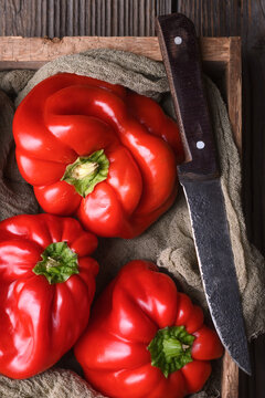 Close up of red bell peppers in crate with knife detail. Fresh sweet peppers, natural harvest theme