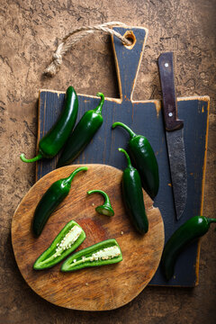 Black jalapeno with knife on rustic wooden cutting board close up. Green mexican jalapeno hot peppers