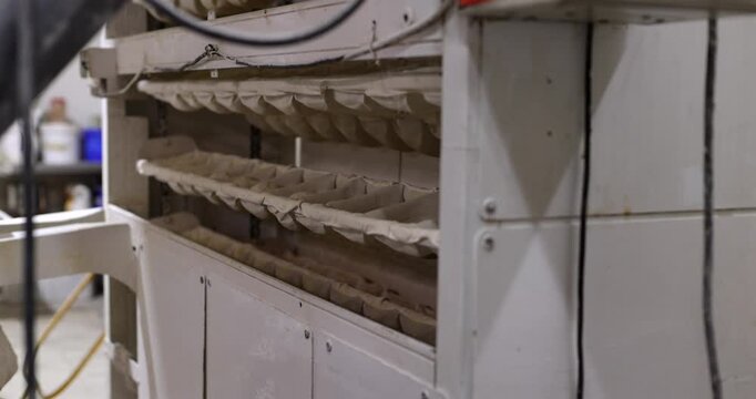Industrial bread proofer machine with canvas pockets containing dough rising and fermenting while moving along the automated conveyor belt system in a commercial bakery plant