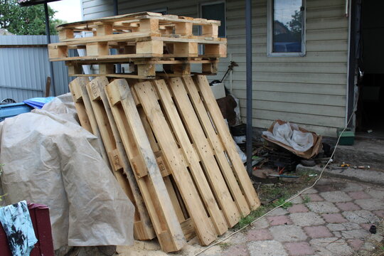 Stacked wooden pallets in the backyard near a rustic village barn.