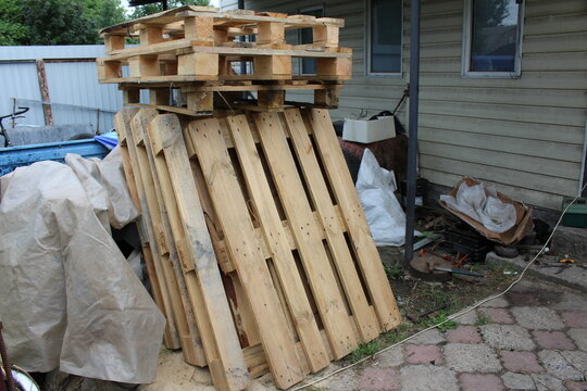 Stacked wooden pallets in the backyard near a rustic village barn.