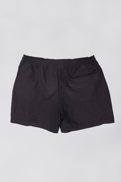 Men's dark brown sports shorts flat lay back view isolated on white background. Features elastic waistband and zippered back pocket. Clean product shot for activewear and apparel mockup.