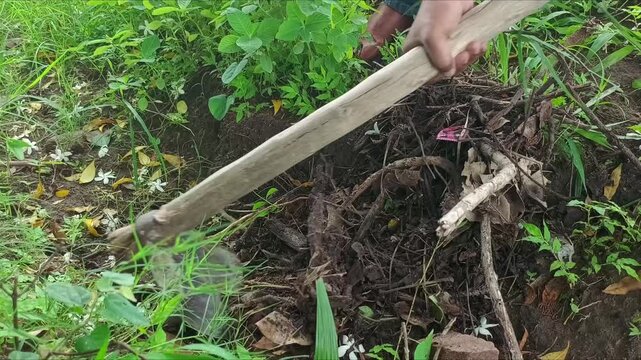 Farmer digging ground and clearing weeds with traditional hoe tool outdoors close up