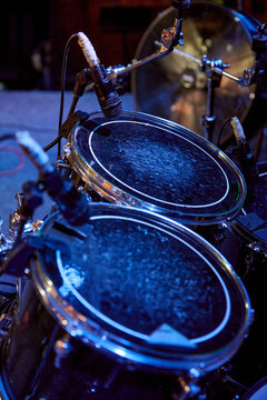Drum kit resonates on stage beneath cool blue concert lighting