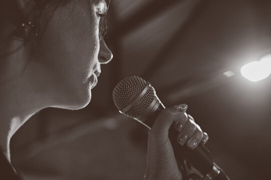 Female singer performs sound check onstage under warm spotlight