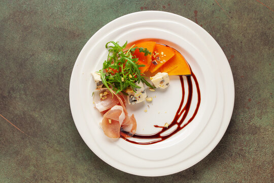 Aperitif salad with persimmon, prosciutto, arugula and cheese