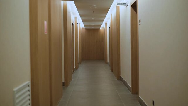 The hallway contains multiple closed doors on either side, with a neutral color scheme and bright overhead lighting