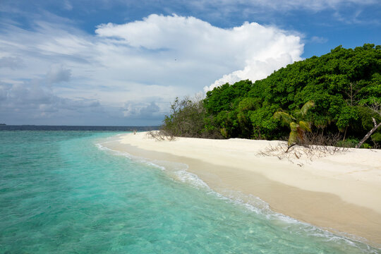 A narrow sandbank curves along clear turquoise water toward a distant island, Baa Atoll, Soneva Fushi, Maldives