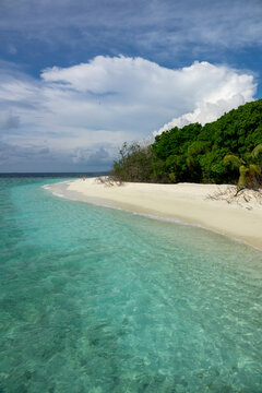 Turquoise water washes over a sandy point beneath a cloudy sky, Baa Atoll, Soneva Fushi, Maldives