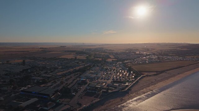 Leysdown Beach coastline during a partial solar eclipse, with the sun above the horizon and seaside below, wide aerial view