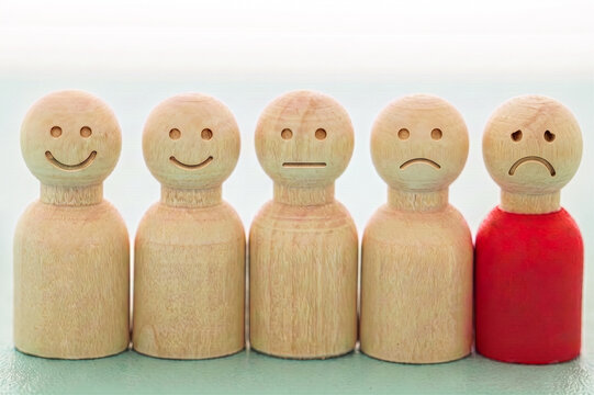 Concept of satisfaction and mood, represented by wooden tokens featuring expressions ranging from happy to sad or angry.