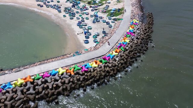 Cinematic aerial drone footage highlighting colorful coastal wave breakers and traditional round basket boats docked along the scenic beach in Mui Ne, Vietnam.