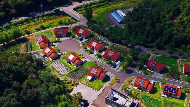 Aerial parallax over planned village of matching red roof houses with rooftop solar panels kitchen gardens and cul de sac road surrounded by pine forest in Geumsan South Korea