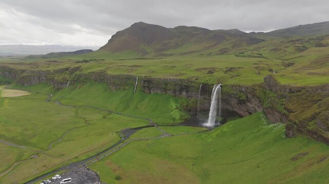 Seljalandsfoss waterfall cascading from green cliffs in southern Iceland, aerial establishing overview