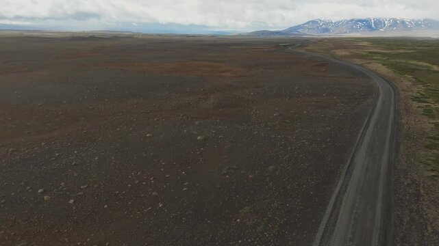 Road F35 crossing barren volcanic highlands near Langjokull in Iceland, aerial pullback along roadway