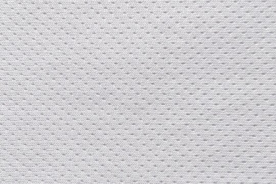 Close-up macro texture of white breathable mesh polyester fabric, athletic sportswear jersey cloth background.