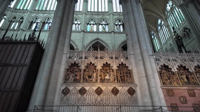 Detailed view of the ornate choir screen inside Amiens Cathedral, featuring carved biblical scenes, Gothic tracery, stained glass and monumental stonework