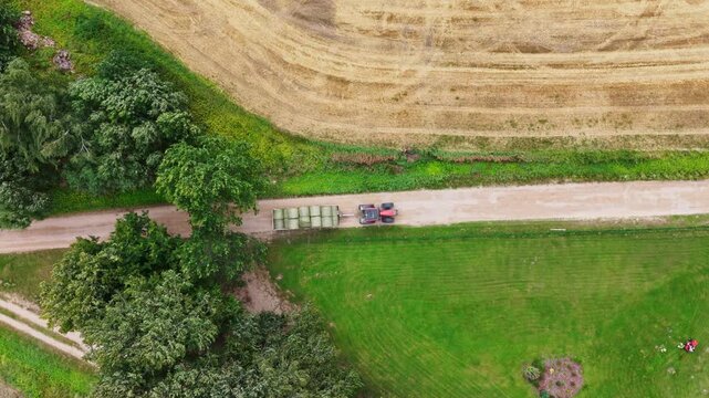 Top down aerial footage tracks a tractor on a rural road in Talsi Municipality