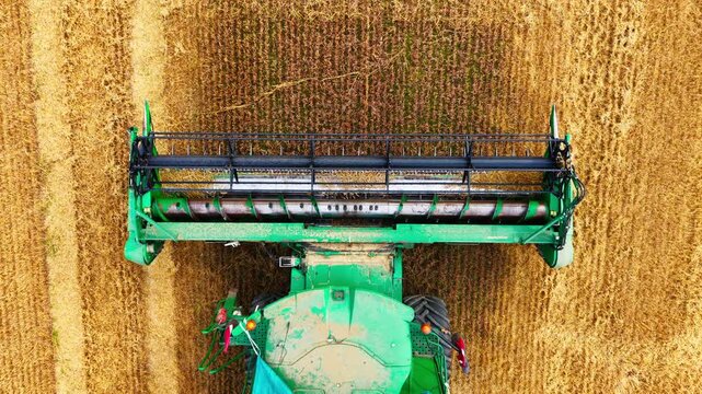Top down aerial view shows parked combine as drone gently lowers over farmland