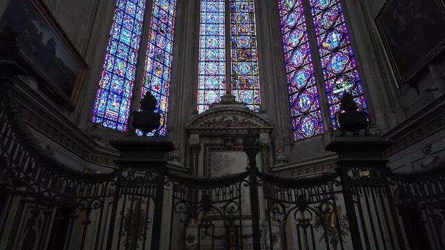 Amiens Cathedral, framed by an ornate wrought iron screen beneath vivid stained glass windows and carved stonework