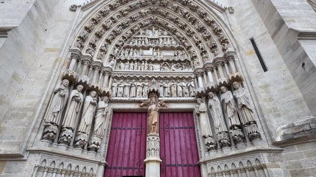 Amiens Cathedral, featuring rows of medieval sculptures, intricate stone carvings and distinctive red doors